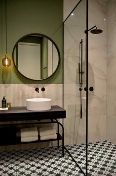 a bathroom with black and white flooring and a round mirror on the wall above the sink