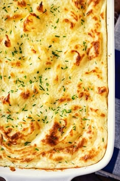 a casserole dish with cheese and herbs in it sitting on a blue checkered table cloth