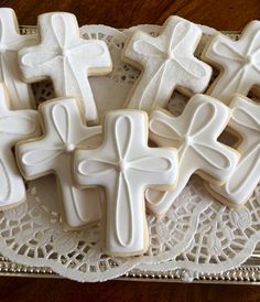 cookies decorated with white frosting and crucifixs on a doily