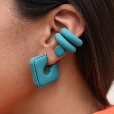 a close up of a person wearing large blue earrings and an orange shirt