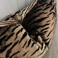 a zebra print pillow sitting on top of a wooden floor next to a white wall