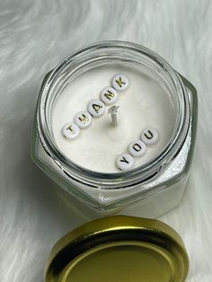 a glass jar with the word thank you spelled in small letters on it next to a gold lid