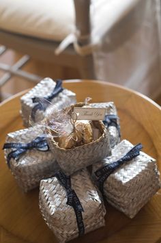 four wrapped gift bags sitting on top of a wooden table next to a white couch