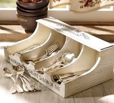 a wooden box filled with silverware on top of a table