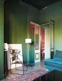 a living room with green walls and a blue couch next to a fire place in the corner