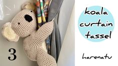 a crocheted teddy bear hanging on the side of a wall with pencils in it