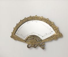 a decorative mirror with an ornate design on the front and back side, hanging on a wall