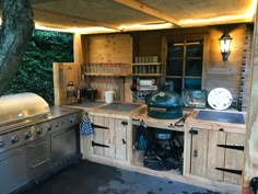 an outdoor kitchen is built into the side of a building with wood paneling and cabinets