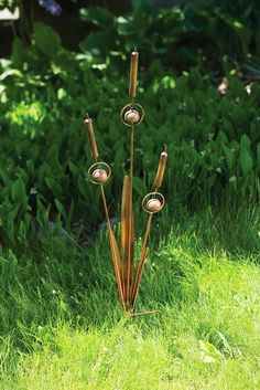 a metal sculpture in the middle of some grass