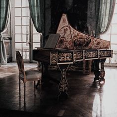 a grand piano sitting in the middle of a room next to a chair and table