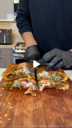 a person in black gloves cutting up food on a wooden cutting board with a knife