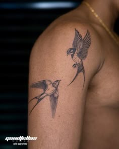 two birds flying next to each other on the back of a man's arm