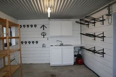 a kitchen area with white cabinets and black piping on the wall, along with ladders