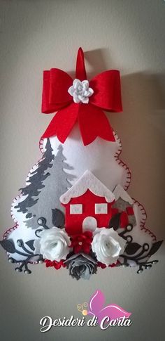 a red and white christmas tree with a house on it's side, hanging from the wall