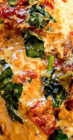 a pizza with spinach, cheese and sauce on it sitting on a table top