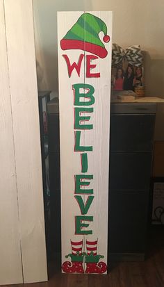 a wooden sign with the words we believe and an elf's hat on it