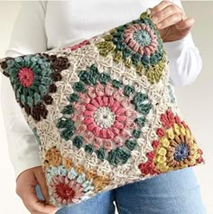 a woman is holding a crocheted pillow with flowers on the front and sides