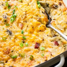 a casserole dish with green onions, cheese and meat in it on a white plate