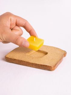 a hand is placing a piece of cheese on top of a slice of bread that has been placed on it