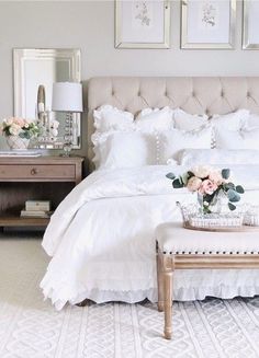 a bed with white linens and flowers on the headboard, along with two side tables