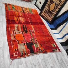 an orange rug on the floor next to other rugs