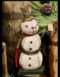 a snowman with a top hat and red scarf standing in front of a wooden barrel