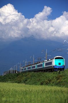 a blue and white train traveling down tracks next to power lines under a cloudy sky