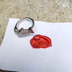 a piece of paper with a ring on it next to a red object that looks like a fish