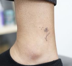 a small dandelion tattoo on the side of a woman's neck is shown