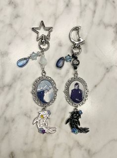 two key chains with charms attached to them on a marble surface, one has an image of a woman and the other is a dog