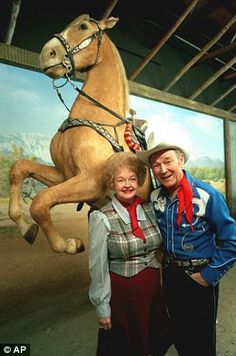 two people standing next to each other in front of a large horse on the wall