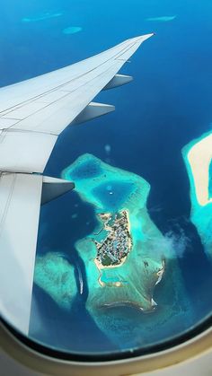 an airplane wing is flying over the ocean and islands in the water with houses on them