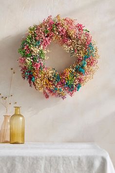 a wreath is hanging on the wall next to two vases