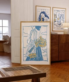 three framed art work on the wall in a room with wood floors and wooden furniture