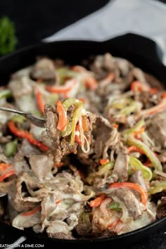 a spoon full of food with meat and vegetables on the side in a skillet