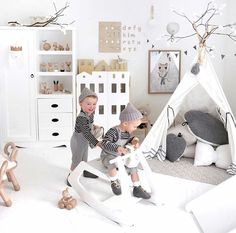 two small children playing in a playroom with teepee tent and toys on the floor