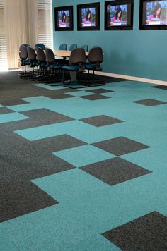 an empty conference room with chairs and televisions on the wall behind them in front of a checkerboard pattern floor