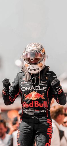 a man in black and red racing suit standing on top of a race track