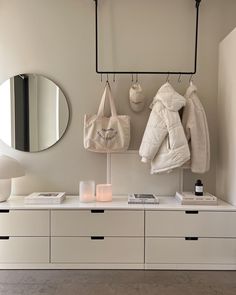 a coat rack with two coats hanging from it's hooks next to a white dresser