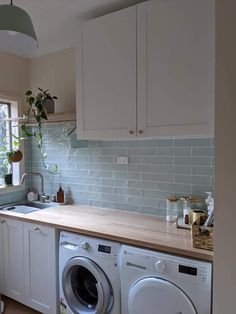 a washer and dryer sitting in a kitchen next to a window with potted plants