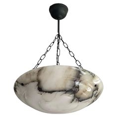 a white and black marble bowl hanging from a metal chandelier with chain links