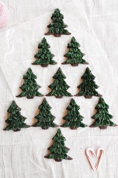 small christmas trees are arranged in rows on a white tablecloth next to a pair of scissors