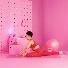 a woman in red is doing yoga on a pink floor with balloons and lights behind her