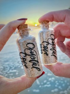 two people holding small bottles with writing on them