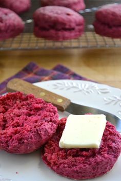 two red velvet cookies on a white plate with a butter knife next to it and a block of butter