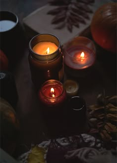 three candles are lit on a table surrounded by autumn leaves and acornal decorations