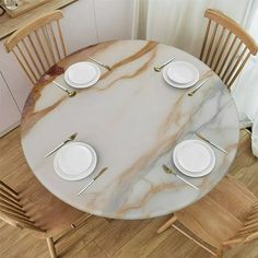 a marble table with white plates and silverware on it, in front of a window