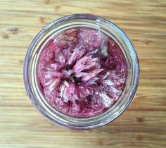 a jar filled with pink flowers sitting on top of a wooden table