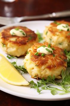 three crab cakes on a white plate with lemon wedges and parsley garnish