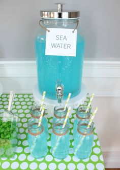 a table topped with mason jars filled with blue liquid and drinking glasses on top of it